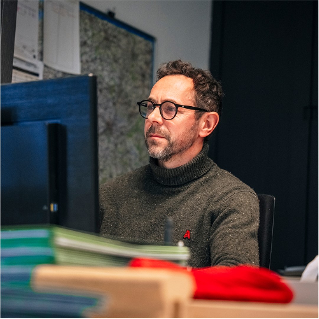 A craftsman working on a wooden staircase in a bright workshop, surrounded by tools and wood materials, focused and dedicated atmosphere
